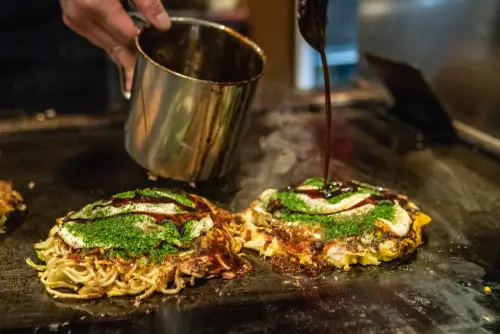 料理人が鉄板の上でお好み焼きを焼く様子